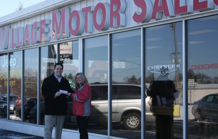 File photo. Athletic Director Jeremy Barkey accepts a check from Tammy Burgess of Vilage Motor Sales.
