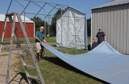 Lions Club members unwrap the tarp that goes on top of the dunk tank. 