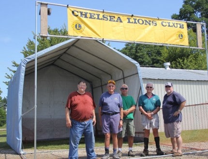 Chelsea Lions Club members take a break from setting up the dunk tank Saturday to pose for a photo. 