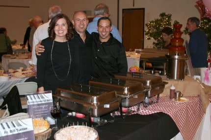 Photo by Kelly Flaherty. Jennifer, Phil, and Jason Tolliver from Smokehouse 52 and hot trays of sausage, pork lollipops, and smoked turkey. 