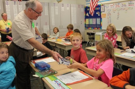 Kiwanian Don Cole hands out dictionaries to third-graders at South Meadows Elementary School. 