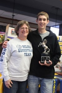Weston Barnes, the only senior on the Chelsea Equestrian Team holds one of the many trophies the team won. With his is Head Coach Lucy Heimerdinger.