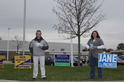 Dustin Suntheimer and Jane Pacheco stand near their signs outside the polling place Tuesday afternoon.