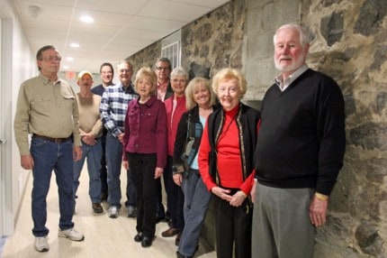 Members of the Grossman Committee stand beside the original north wall of the church in the basement.