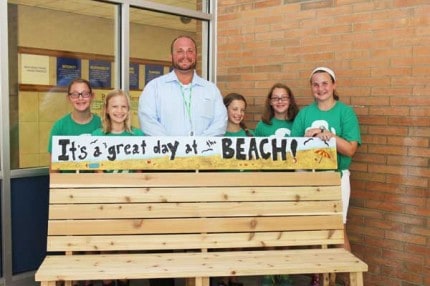 MacKenna Lamb, Jessica Stahl, Principal Nick Angel, Emma Frederiksen, Molly Lamb and Katherine Thoms stand behind the new bench at Beach Middle School.
