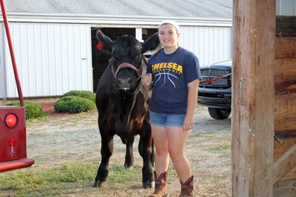 Mackenzie Schneider, 14, and Diesel, enter the cattle barn at the Chelsea Community Fair Monday night. 