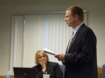 Photo by Crystal Hayduk. Nathan Baldermann of Rehmann Robson gives his audit report to the school board as Teresa Zigman, executive director of business and operations, listens.