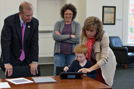 Courtesy photo. Congressman Tim Walberg watches child use new app developed  by Tricia at Chelsea District Library.