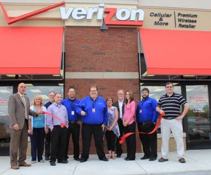 Erik Fetters cuts the ribbon at Friday afternoon's Chelsea Area Chamber of Commerce celebration of the Cellular and More Verizon Wireless Premiere Retailer. He is flanked by store employees and chamber members. 