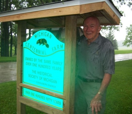 Donald Doll stands in the rain next to the new sign at the Doll Family Farm.