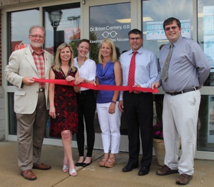 Chelsea Chamber of Commerce Executive Director Bob Pierce on left, Chelsea Optometry staff in the center and Chamber of Commerce Board President Ian Boone on right at the ribbon cutting Wednesday afternoon.