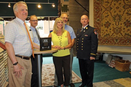 Tim Merkel, owner, Tony Archer, sales manager, Diane Holley of Mohawk Carpet, Fred Zuidveld, owner and Charlie Gussman, retired battalion chief and the commemorative World Trade Towers shadowbox containing a piece of the towers. 