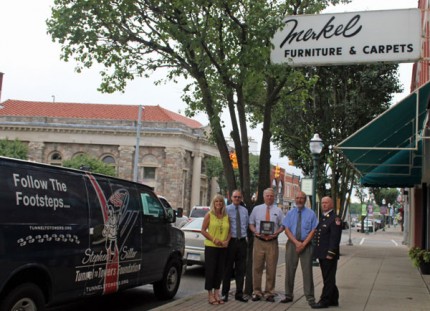 Outside Merkel's Furniture and Carpet, the group stands next to the Stephen Siller Tunnel to Towers Foundation van. 