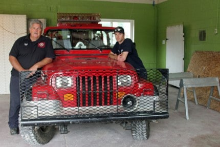 Fire Chief Jim Payeur (left) and Firefighter Ian Ballard pose with the brush truck that is in the second of two bays in the new fire station.