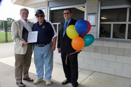 Bob Pierce, executive director of the Chelsea Area Chamber of Commerce presents Ed Vleck with the 2015 Citizen of the Year proclamation on right Chamber Board President Ian Boone holding the balloons.