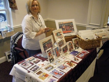 Photo by Jim Pruitt. The 2015 Harvest Art Sale at Silver Maples in Chelsea attracted a full house of artists who were selling their creations. Tammy Burke shows her collection of watercolors of animals and old buildings in Chelsea.