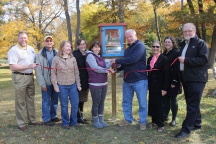 The ribbon is officially cut at the Little Free Library in Pierce Park on Oct. 22 by Sue Whitmarsh, presidents of the Friends of the Library and Gary Muncie, who helped to plant the little library.