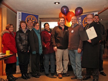 Paul Schissler of Surface Dynamics (center in brown sweater) was surprised at a Rotary meeting Tuesday afternoon as the 2015 Small Business Leadership Award winner.
