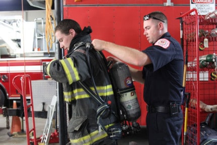 Firefighter James Gaken gets help putting on the new air pack from Lt. Bill Rignier.