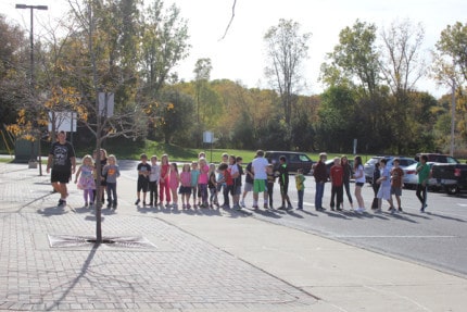 After evacuating their bus, students go to a gathering spot during a bus evacuation drill. 
