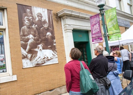 Photo by Burrill Strong. Visitors look at one of the 36 WWI banners displayed in Chelsea. 